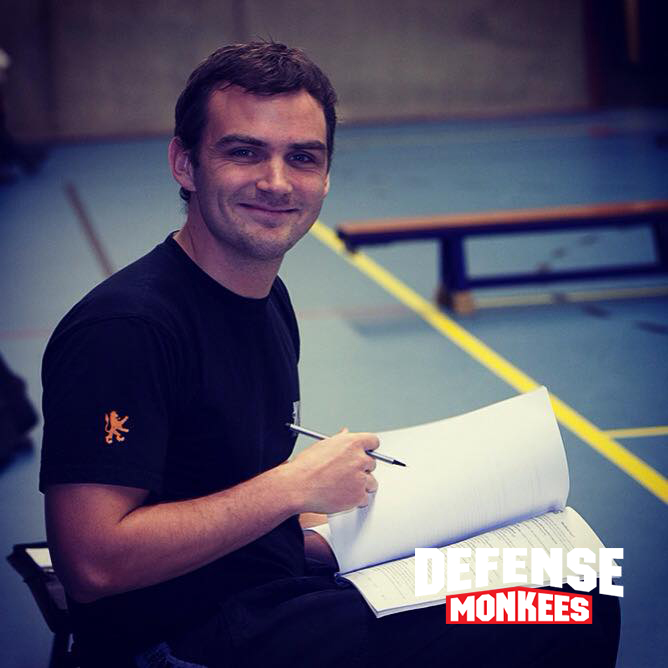 Krav Maga instructeur van DefenseMonkees observeert en coacht een groepsles zelfverdediging in de sportschool, met focus op veiligheid en techniek.